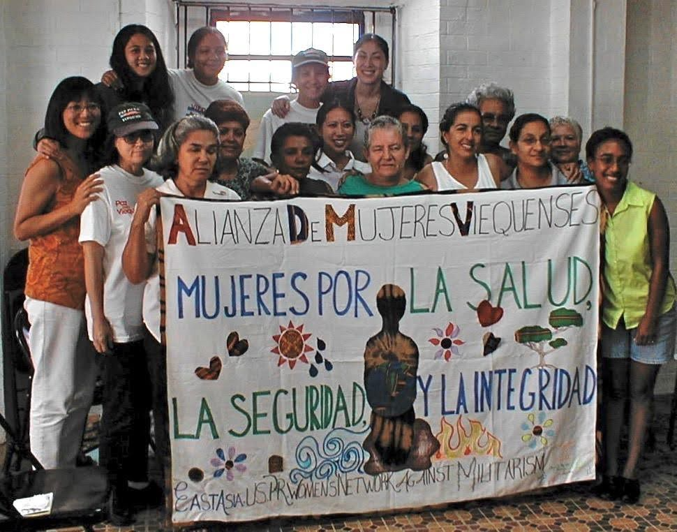 Figure 2. WOMEN FOR HEALTH, SECURITY, AND WHOLENESS
This banner was made in 2001 by women from the continental US on a solidarity visit to Vieques Women’s Alliance. They were involved in a major campaign, ultimately successful, to stop the US Navy’s live bombing training on Vieques, which had displaced residents from a-third of the island, littered the land with unexploded munitions and other military trash, and contaminated land, water, and ocean. Severe environmental damage, cancers, and leukemia are among its terrible legacies left to the local community.