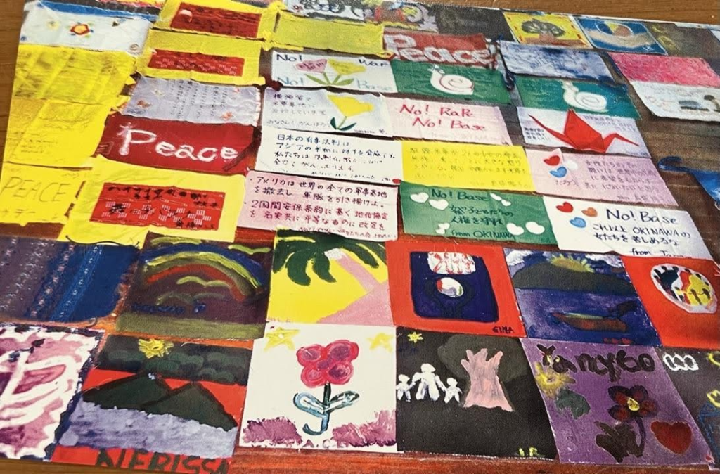 Figures 4. PEACE & FRIENDSHIP QUILT
2002 4th international meeting in South Korea. Participants decorated small squares of cloth with paint and markers for the hosts to assemble after the gathering. 
Photo: Don Mee Choi.