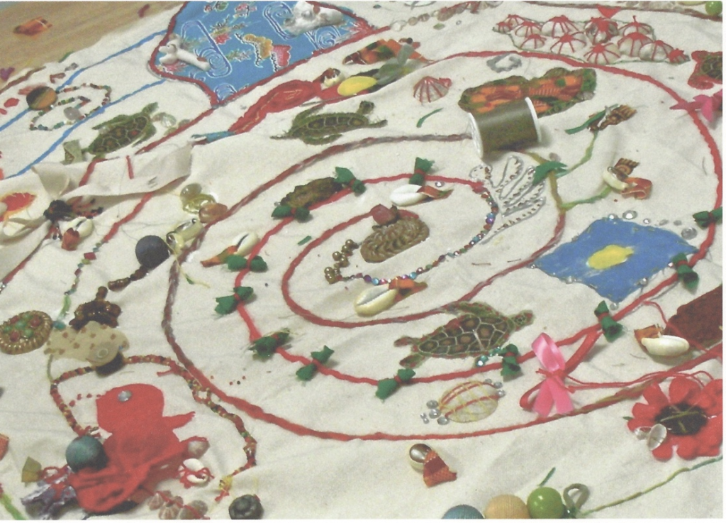 Figure 9. Fabric decorated at the International meeting in Guåhan (Guam) in 2009. This was created over several days in a free-form style by anyone who wanted to add to it, and includes fabric pieces, embroidery, beads, pebbles, and shells.