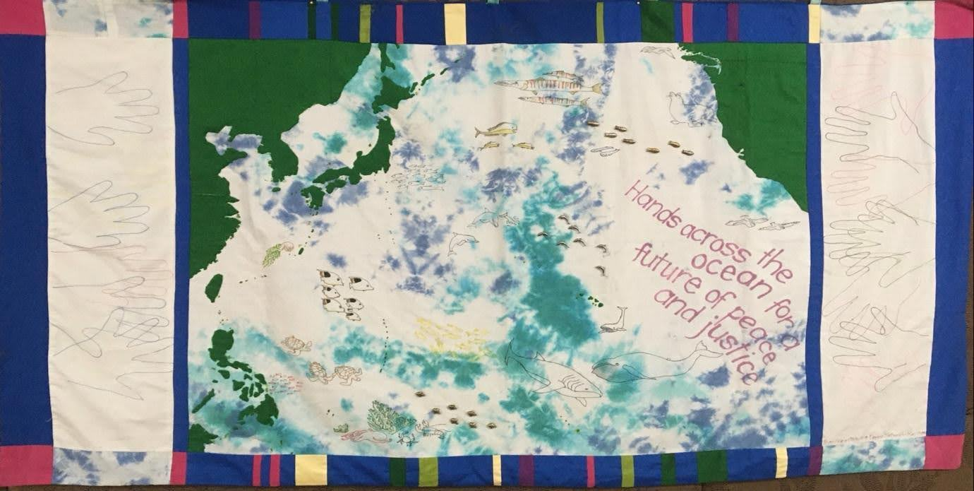 Figure 1. HANDS ACROSS THE OCEAN
Women in California and Okinawa made this map in 1998, drawing around their hands and reaching out across a tie-dyed Pacific Ocean. Okinawa women have taken this banner to many rallies and meetings since then. Created: Carolyn Francis and Gwyn Kirk.